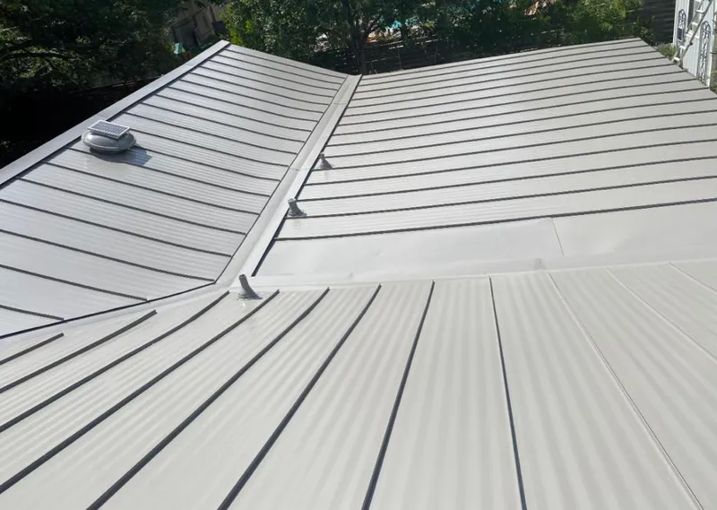 Solar attic fan installed on a metal roof for Roof Ventilation in Lansing